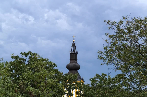 Szczyt Kościoła między drzewami i niebem z daleka — Zdjęcie stockowe