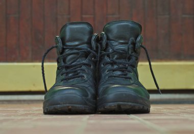 Bir çift siyah ayakkabı seramik fayansların üzerinde kapının önünde.