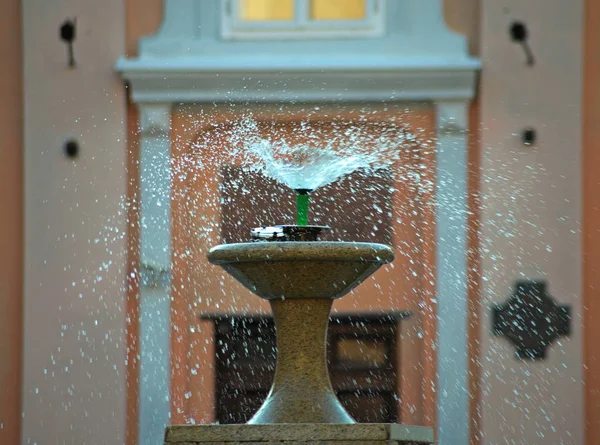 Droplets dispersing from a fountain and buildings in background — Stock Photo, Image