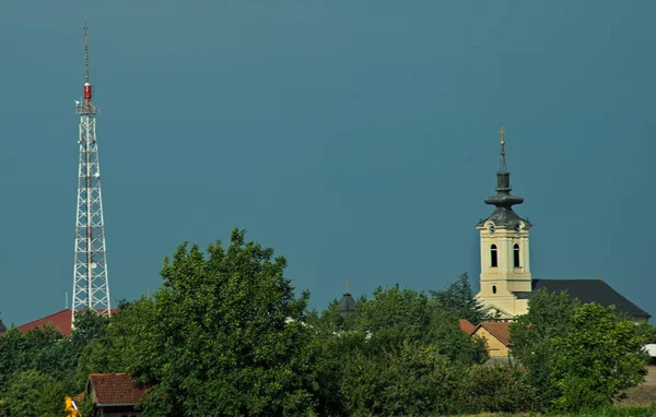 Torre radio e torre della chiesa che spuntano sopra gli alberi — Foto Stock