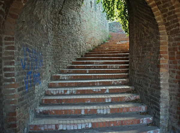 붉은 벽돌들은 끝에서 빛을 받으며 위로 올라가는 계단 통로이다 — 스톡 사진