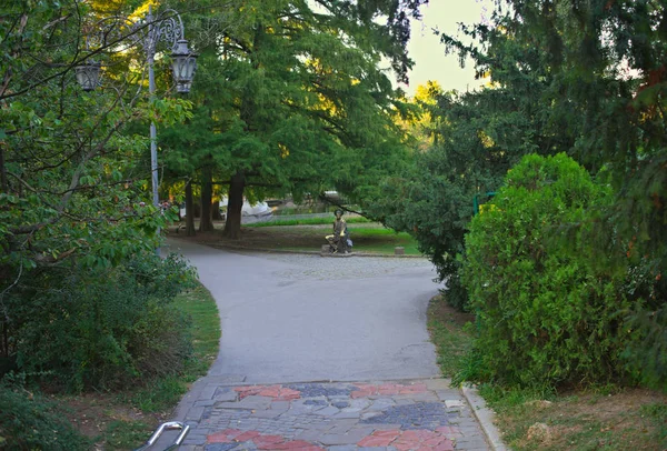 Caminho do parque com vegetação ao redor e monumento na encruzilhada — Fotografia de Stock