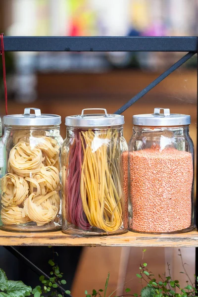 Pasta in the jar. On kitchen shelves are different kinds of pasta in glass jars. Meal, italy