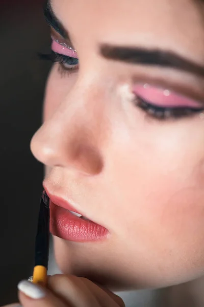 La mano del maestro del maquillaje, pintando los labios del modelo joven hermoso . — Foto de Stock