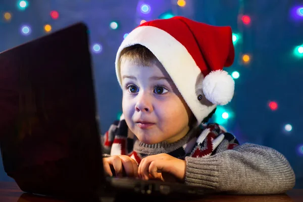 Little child writing letter to Santa Claus on laptop computer. Winter holiday Xmas and New Year concept.