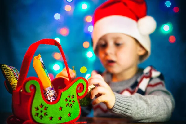 Ein Süßer Junge Mit Hut Weihnachtsmänner Betrachtet Ein Geschenk Süßigkeiten — Stockfoto