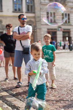 Lviv, Ukrayna - 12 Ağustos 2018: sabun kabarcıkları ile Lviv ana kare üzerinde oynarken mutlu küçük çocuk. Lviv tarihi kent. Mutlu çocuk.