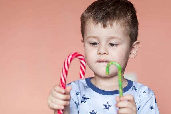 Un garçon mignon tenant deux bâtons de bonbons . — Photo