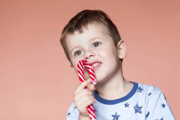 Ein süßer Junge, der Zuckerstangen isst. farbige traditionelle handgemachte Zuckerstangen — Stockfoto