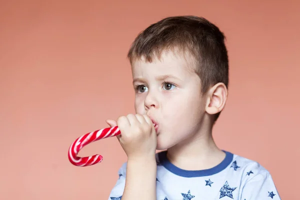 A cute boy eating candy sticks. Colored traditional handmade candy canes