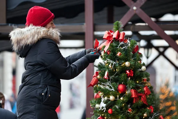 Woman decorating Christmas tree outside. Outdoor Christmas Decor.