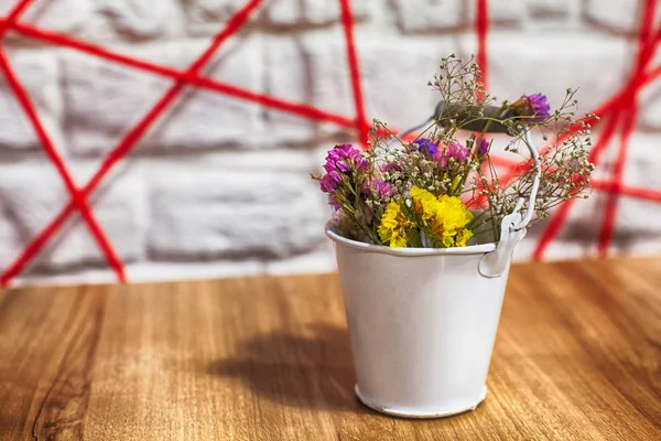 Dried flowers in a white bucket, Bucket with Dried flower on wood background. The decorations of the cafe.