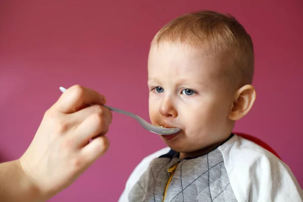 Mamá alimenta a su hermoso bebé con una cuchara. Sopa de pollo saludable — Foto de Stock