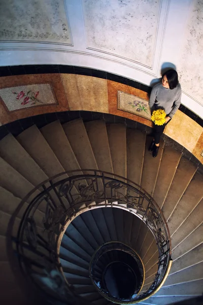 Молода красива жінка стоїть на старих круглих спіральних сходах. Вид зверху . — стокове фото