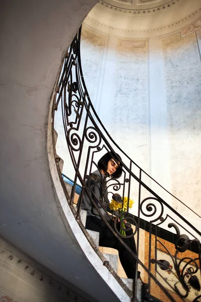 Молода красива жінка сидить на старих круглих спіральних сходах . — стокове фото
