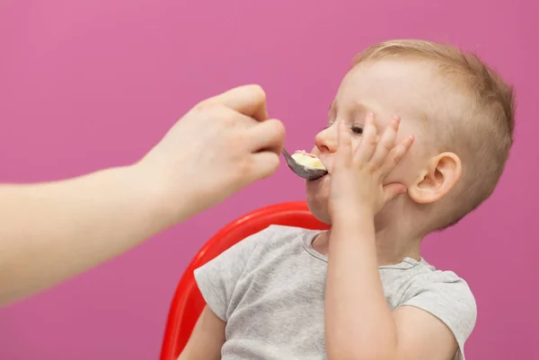 El niño no quiere comer puré de papas. El niño desayuna en casa, mientras ve dibujos animados en la tableta — Foto de Stock