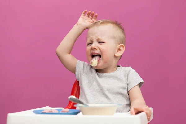 Petit garçon ne veut pas manger de purée de pommes de terre. Enfant mange le petit déjeuner à la maison, tout en regardant bande dessinée sur tablette — Photo