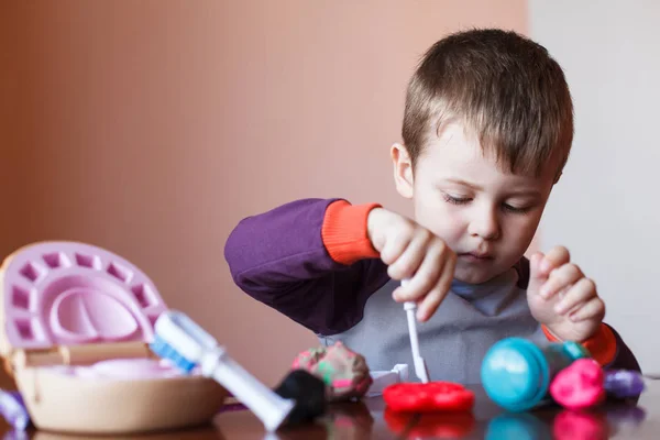 Sevimli küçük çocuk çok renkli plasticine ile oynuyor. Oyuncaklarla oynayan çocuk Diş Aletleri. Yüz ifadesi. Olumlu, olumsuz duygular.