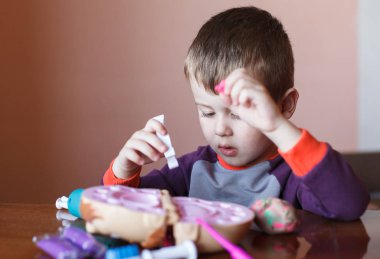 Sevimli küçük çocuk çok renkli plasticine ile oynuyor. Oyuncaklarla oynayan çocuk Diş Aletleri. Yüz ifadesi. Olumlu, olumsuz duygular.