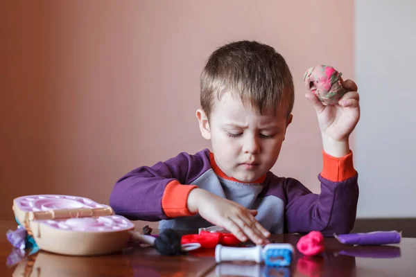 Bonito menino brincando com plasticina de muitas cores. Menino brincando com brinquedos Ferramentas Dentárias. Expressão facial. Emoções positivas e negativas . — Fotografia de Stock