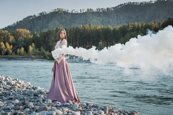 Mädchen Mit Rauchbombe Ufer Eines Gebirgsflusses Mit Weißem Rauch Bergen lizenzfreie Stockfotos