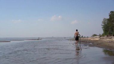 Bir genç adam adımları ile bir tahta bir skimboard için ve kıyı