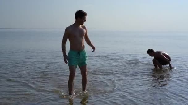 Twee Jonge Mannen Ondiep Water Een Wandeling Uit Het Water — Stockvideo