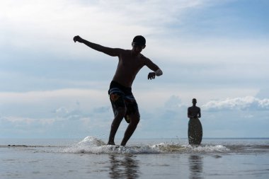 spor ile skimboarding plaj üzerine sığ suda bir su sporu yapan genç erkek silüeti 