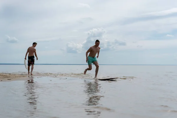 a young man goes in for water sports with skimboarding in shallow water on the shore