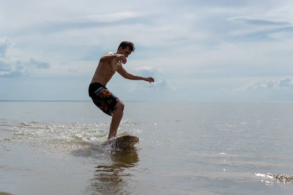 su sporları ile skimboarding plaj üzerine sığ suda ile spor yapan bir genç erkek silüeti 