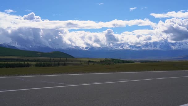 草原と雲の下の山々 の背景に道路 — ストック動画