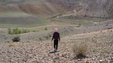 Kız tepeler ve dağlar arka planda ıssız bir taş arazi boyunca yürüyüş.