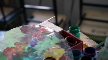 Boyalar, fırçalar ve bir palet tablo yakın çekim vardır. Sığ derinlik-in tarla.