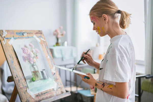 Ein Junges Künstlermädchen Mit Gesicht Und Kleidung Der Farbe Malt lizenzfreie Stockfotos