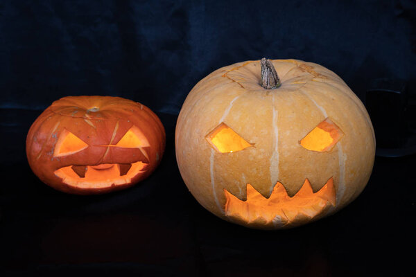 Two pumpkins for halloween on a dark background.