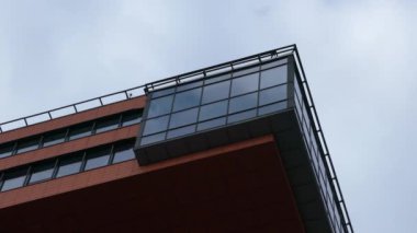 Parlak gökyüzü ve uçan bulutların arka planı üzerinde modern bir binanın parçası.