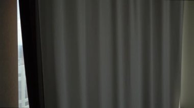 Adam şehre bakan pencerelerde perdeyi açar.