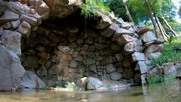 Fontein van stenen met een grot In een tuin — Stockvideo