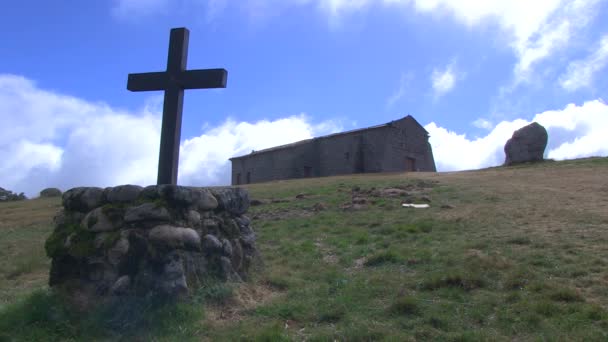 Kreuz in einem Stein und dahinter ein Kloster mit schnellen Wolken — Stockvideo