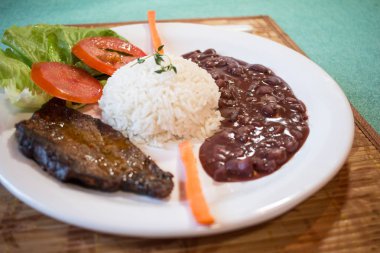 Brasileirinho - Brezilya fasulye pilav ile tipik çanak salata marul, domates ve havuç ve biftek ile yapılmış..