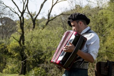 Açık havada mızıka çalan tipik kostümlü Gaucho çocuğu..
