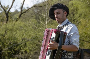 Açık havada mızıka çalan tipik kostümlü Gaucho çocuğu..