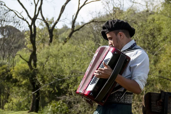 Açık havada mızıka çalan tipik kostümlü Gaucho çocuğu..