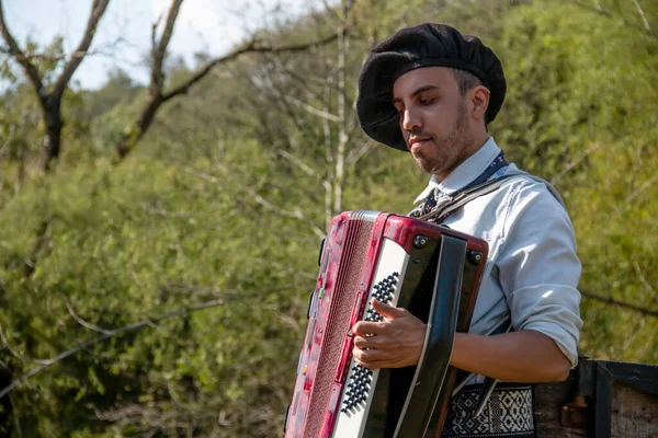 Açık havada mızıka çalan tipik kostümlü Gaucho çocuğu..