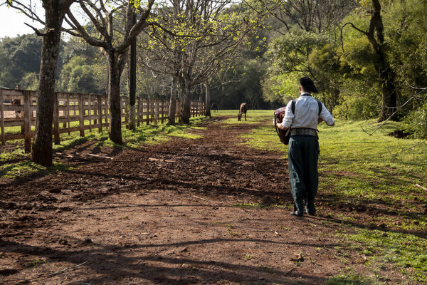 Gaucho playing the harmonica while standing.