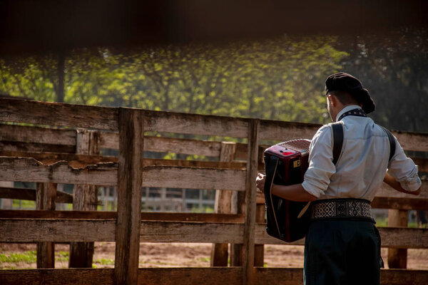 Gaucho boy with typical costumes playing the harmonica outdoors.