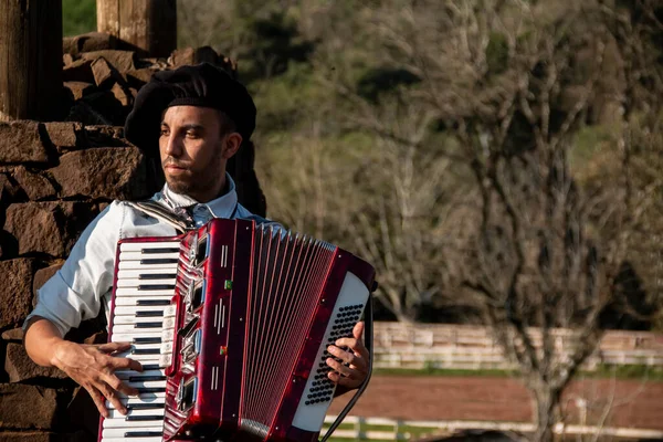 Garoto gaúcho com trajes típicos tocando a harmónica ao ar livre. — Fotografia de Stock