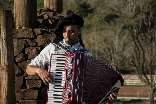 Garoto gaúcho com trajes típicos tocando a harmónica ao ar livre. — Fotografia de Stock