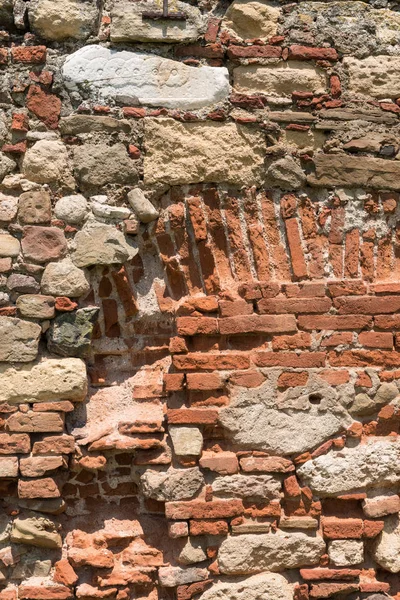 Gri tonlarında kalın harç ve çok sert, düzensiz yüzey ile eski tuğla ve taş duvar.