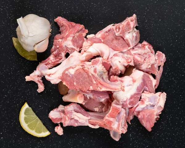 Taze çiğ keçi et güveç gibi kesim siyah kesme tahtası sarımsak ve limon ile.
